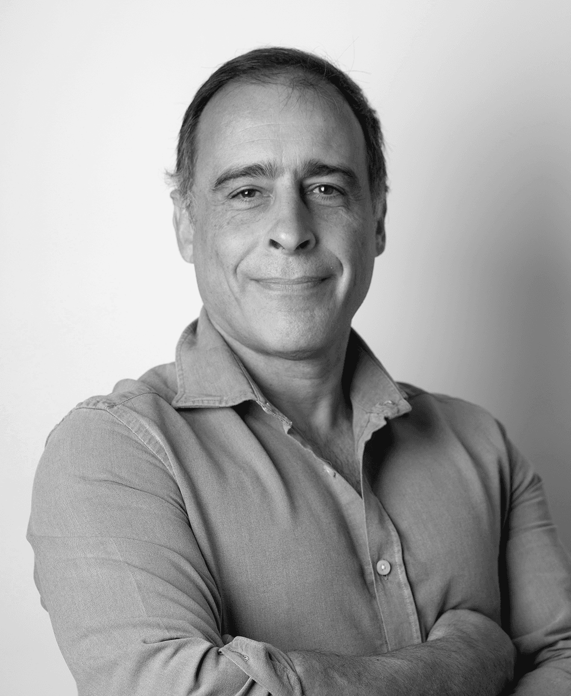Jose Maria Mascarenhas stands in front of a white wall, wearing a shirt, smiling slightly at the camera
