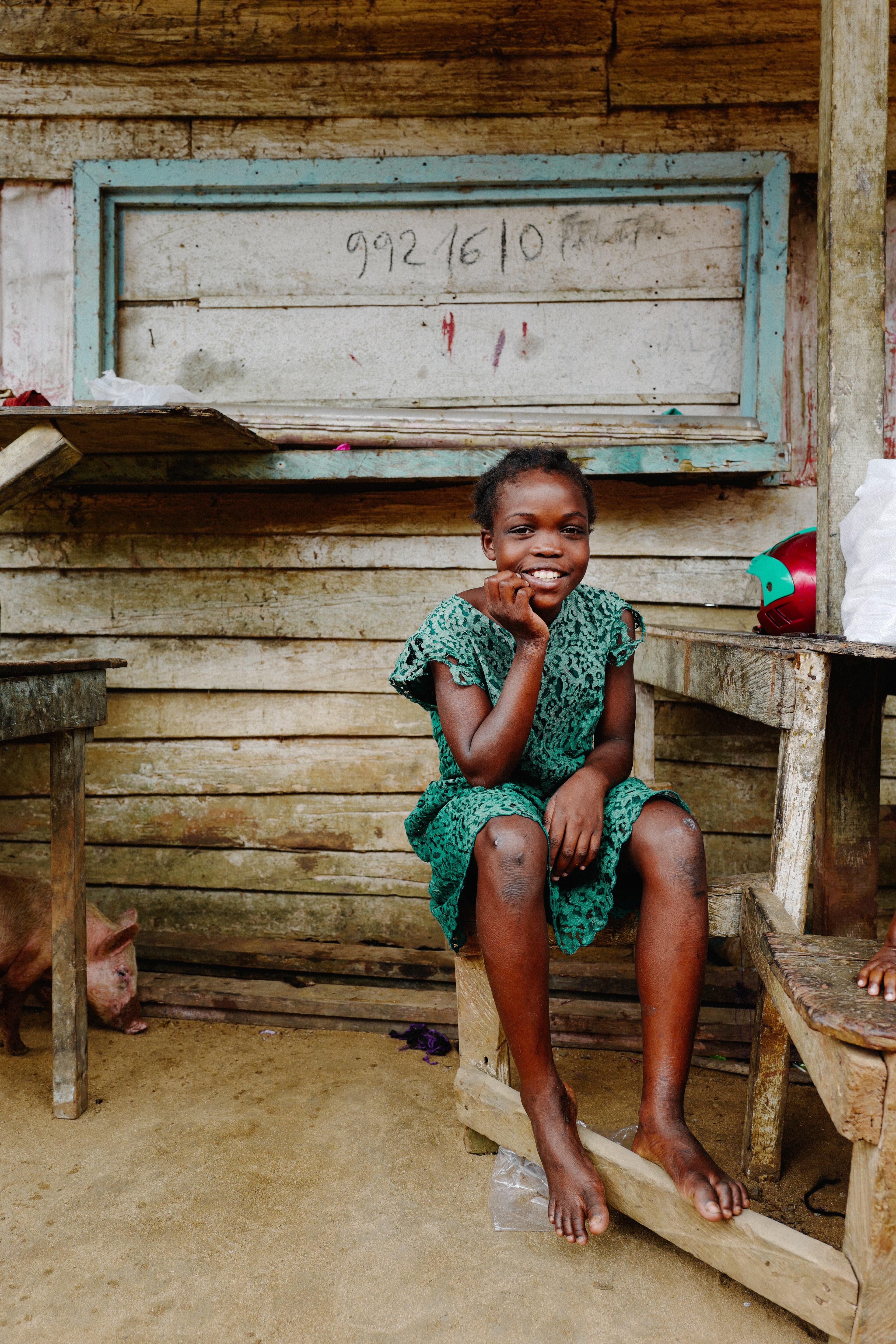 Young girl in a green dress sits in the classroom, laughing at the camera